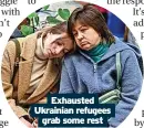  ?? ?? Exhausted Ukrainian refugees grab some rest