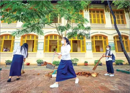  ?? HONG MENEA ?? Students sweep the grounds at Preah Sisowath High School on the first day of reopening, on Wednesday.