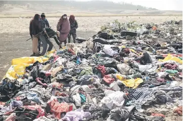  ??  ?? Ethiopian policemen search through the passengers’ belongings at the scene of the Ethiopian Airlines Flight ET 302 plane crash. — Reuters photo