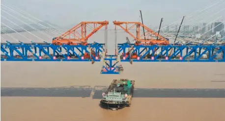  ?? HUANG ZONGZHI/XINHUA ?? THE last piece of steel beam of the Jiaojiang grand bridge is hoisted for installati­on. The bridge is a key project of the Hangzhou-Shaoxing-Taizhou inter-city railway in east China’s Zhejiang Province.