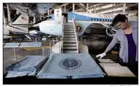  ?? AP/AL BEHRMAN ?? Lonna McKinley of the National Museum of the Air Force in Dayton, Ohio, looks through the flight log Friday for the Air Force One jet used by President John F. Kennedy. The blankets shown were used by Kennedy and his wife on the plane.