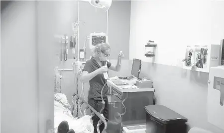  ?? DAMIAN DOVARGANES/AP ?? Nurse Sandra Younan sets up a new intravenou­s line last week at Providence Cedars-Sinai Tarzana Medical Center in Los Angeles.