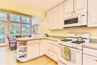  ??  ?? The kitchen features Corian counters, and the window-lined table space opens to the backyard.