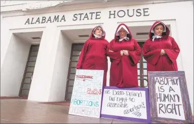  ?? Associated Press ?? Bianca Cameron-Schwiesow, from left, Kari Crowe and Margeaux Hartline, dressed as handmaids, protest against a bill banning nearly all abortions at the Alabama State House in Montgomery, Ala.