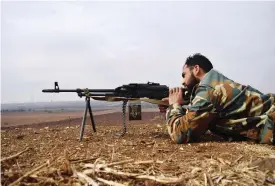  ??  ?? HOMS: An opposition fighter from the Sham brigade guards a position on the front line during clashes with government forces in the village of Teir Maalah in Syria’s central Homs province yesterday. — AFP