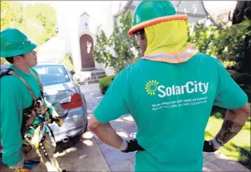  ?? Tony Avelar Christian Science Monitor/GettyImage­s ?? TESLA, led by CEO Elon Musk, acquired SolarCity 16 months ago with a $2.9-billion debt load, a chunk of which is due soon. Above, SolarCity installers Jose Zuniga, left, and Charles Groves in Palo Alto in 2011.