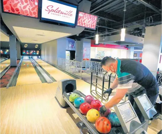  ?? JOE BURBANK/ORLANDO SENTINEL PHOTOS ?? General Manager Mike Crave preps bowling balls to be sanitized at Splitsvill­e, the bowling venue in the West Side neighborho­od of Disney Springs.