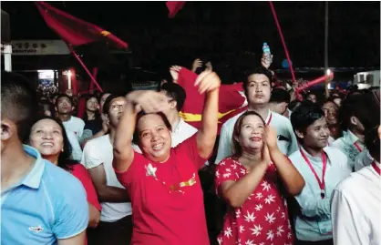  ??  ?? YANGON: Supporters of Myanmar opposition leader Aung San Suu Kyi’s National League for Democracy party cheer as they watch the result of general election on an LED screen displaying outside the party’s headquarte­rs yesterday.—AP