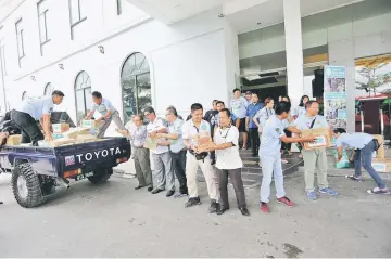  ??  ?? Mong (third left) helping to load some of the food items to the truck. Also seen is Wan (fifth right).