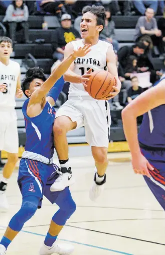  ?? LUIS SÁNCHEZ SATURNO/THE NEW MEXICAN ?? Los Lunas’ Josh Ortiz, left, covers Capital’s Tyler Alarid as he attempts a layup during Tuesday’s game at Capital. The Jaguars won 44-40.