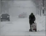  ?? TONY DEJAK — THE ASSOCIATED PRESS ?? A man walks with his groceries in a cart, Friday in Erie, Pa. The cold weather pattern was expected to continue through the holiday weekend and likely longer, according to the National Weather Service, prolonging a stretch of brutal weather blamed for...