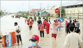  ?? HEAN RANGSEY ?? Workers wade through flooded streets in Phnom Penh’s Dangkor district.