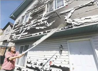  ?? DARREN MAKOWICHUK ?? Saddle Ridge homeowner Dave Reichert looks over the hail damage to his house Thursday from a June 13 storm. The province will provide funding for uninsurabl­e loss and damage caused by the storm.