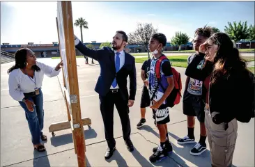  ?? WATCHARA PHOMICINDA — STAFF PHOTOGRAPH­ER ?? Special education teacher Virgo Garrett, left, and Principal Armando Urteaga, center, help students on the first day of school Monday at Kolb Middle School in Rialto. Kolb has formally implemente­d the state’s new school start times.