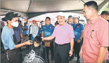  ?? ?? Hajiji visiting a barber stall providing free hair cuts to children during the Gagasan Rakyat Mini Carnival.