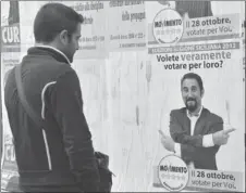  ?? CARMELO IMBESI/AP ?? A man looks at an electoral poster for the Five Star Movement, which is proving a threat to the traditiona­l center-right and center-left parties, in Catania, on the island of Sicily, Italy.