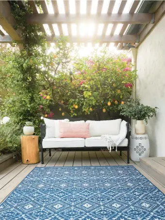  ?? RUGGABLE ?? Washable outdoor rugs, like this one with a navy and white print, are a great way to bring an indoor vibe outdoors.