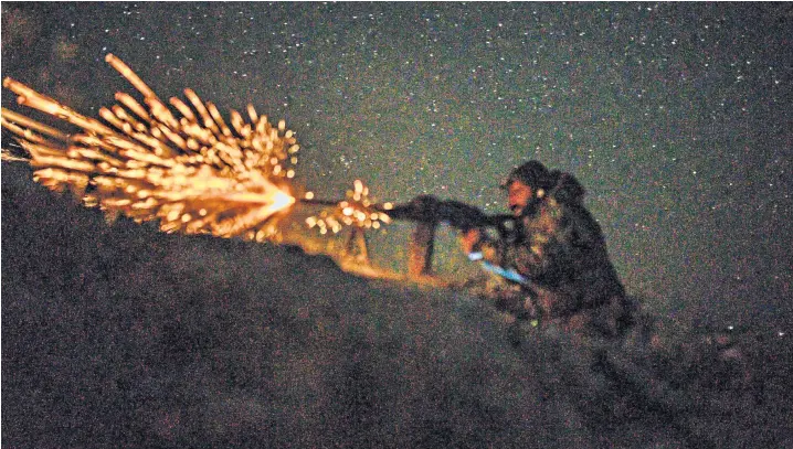  ??  ?? A soldier with the Syrian Democratic Forces fires his machine gun into the Islamic State group’s embattled holdout of Baghouz, in Deir Ezzor province, eastern Syria. Hundreds of Isil fighters are said to have surrendere­d in the latest battles around the enclave