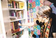  ?? KRISTIAN CARREON ?? Katia Padilla pulls a book from her Little Free Library that she has operated for two years at her Chula Vista home on Tuesday.