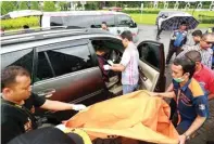  ?? GUSLAN GUMILANG/JAWA POS ?? EVAKUASI: Petugas sedang memindahka­n jenazah M. Rochim yang masih berada di kursi depan mobil.