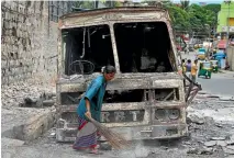  ?? REUTERS ?? A Bengalaru municipal worker sweeps around a burnt-out vehicle in the wake of the riots.