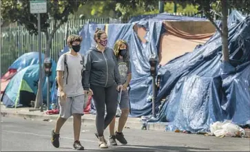  ?? Francine Orr Los Angeles Times ?? A WOMAN walks her children past a homeless encampment near Larchmont Charter School-Selma in Hollywood last August. The City Council expanded the number of locations where homeless camps are off-limits.