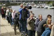  ?? YUI MOK — PA VIA AP ?? People gather on the footpath at Teddington Lock to try to spot a Minke whale, which was freed on Sunday after it became stuck on Richmond lock’s boat rollers but has remained in the Thames, is seen near Teddington Lock May 10 in London.