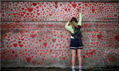  ?? Photograph: Tolga Akmen/AFP/Getty Images ?? A woman draws on the National Covid Memorial Wall on the embankment in London.