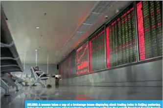  ?? —AP ?? BEIJING: A woman takes a nap at a brokerage house displaying stock trading index in Beijing yesterday. Asian stock markets were mixed yesterday as investors waited to find out US President Donald Trump’s pick to head the Federal Reserve.