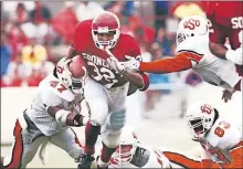  ??  ?? Oklahoma running back Mike Gaddis, center, runs past the outstretch­ed arms of Oklahoma State defenders during the 1991 Bedlam game in Norman. The former Carl Albert High School standout ran for 203 yards on 35 carries on a rain-soaked Owen Field as the Sooners defeated the Cowboys, 21-6. [THE OKLAHOMAN ARCHIVES]