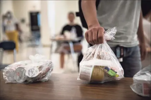  ?? John Moore / Getty Images ?? A student picks up a free individual­ly bagged lunch in the cafeteria during the first day of school at Stamford High School on Sept. 8 in Stamford.