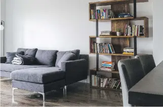  ??  ?? The colour palette is grey and white with warm touches of wood from a zigzag-shaped bookshelf next to Faustini’s charcoal-coloured sectional couch sourced from the furniture store MUST.