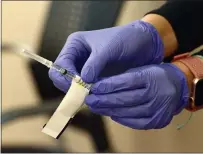  ??  ?? A nurse handles a syringe with a dose of the Pfizer COVID-19 vaccine at Novato Community Hospital.