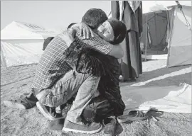  ??  ?? SADA MUSLAT, 71, greets her son Waeed Ahmed Hussein, whom she had not seen in nearly three years, at the Hassan Sham camp.