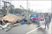  ?? ERWIN MASCARINAS — THE ASSOCIATED PRESS ?? Residents carry what’s left of their belongings as they walk past damaged homes due to Typhoon Rai in Surigao city, Surigao del Norte, central Philippine­s, on Friday.