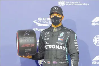  ?? - AFP photo ?? Hamilton poses for a picture with the pole position trophy after the qualifying session of the Bahrain Formula One Grand Prix.