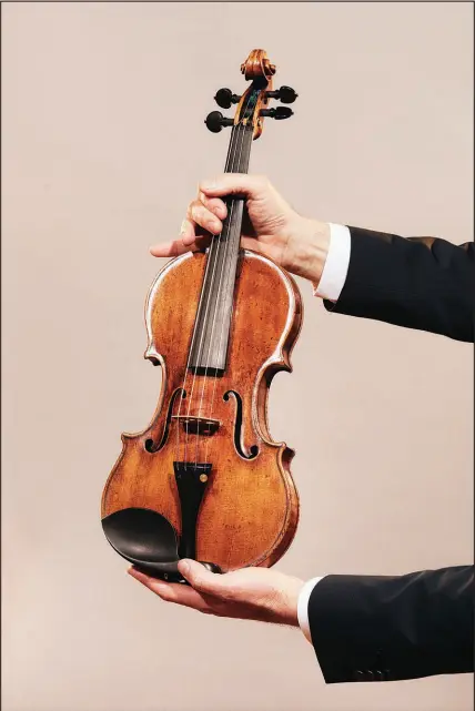  ?? ANDREW WHITE / THE NEW YORK TIMES ?? Jason Price, director of Tarisio auction company, holds the “da Vinci” Stradivari­us violin April 30 in Berlin. Crafted in 1714 and played in “The Wizard of Oz” and other classic films, Toscha Seidel’s Stradivari­us could sell for almost $20 million at an online auction running from May 18 through June 9.