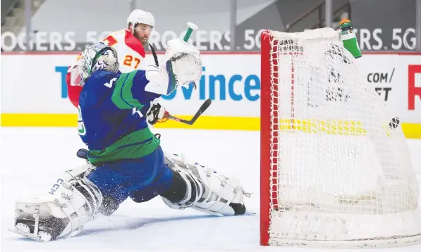  ?? THE CANADIAN PRESS ?? The Flames' Josh Leivo scores on Canucks goalie Braden Holtby in the first period of their game Sunday.