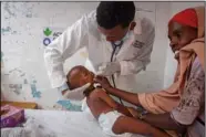  ?? ?? Yusuf treats Ali as his mother Owliyo Hassan Salaad, 40, holds him June 5 at a malnutriti­on stabilizat­ion center in Mogadishu.