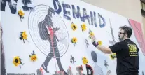  ??  ?? Manuel Oliver places flowers in the holes that represente­d the 17 students of Parkland, Florida, part of a mural in the memory of his son, Joaquin, and the other students, at the Rally4Refo­rm protest to push for gun reform, at City Hall in Dallas...