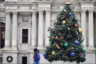  ?? Matt Slocum / Associated Press ?? A person wearing a face mask to protect against the spread of the coronaviru­s walks past holiday decoration­s on Dec. 8 at City Hall in Philadelph­ia. With some Americans now paying the price for what they did over Thanksgivi­ng, health officials are warning people — begging them, even — not to make the same mistake during the Christmas and New Year’s season.