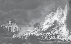  ?? MIKE ELIASON/SANTA BARBARA COUNTY FIRE DEPARTMENT VIA AP ?? Flames from a backfire rise behind a home in Santa Barbara, Calif.