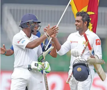  ?? (AFP) ?? Sri Lanka’s Asela Gunaratne (right) and Dilruwan Perera celebrate their team’s win against Zimbabwe in the one-off Test match on Tuesday