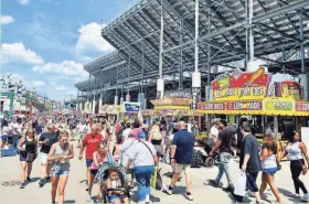  ?? RACHEL RYAN / MILWAUKEE JOURNAL SENTINEL ?? Fairgoers enjoy the opening day of the 2021 Wisconsin State Fair along Grandstand Avenue, the fair’s main roadway and a hot spot for many of the fair’s food options.