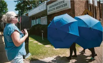  ?? Seth Herald / AFP/Getty Images ?? A protester shouts as a woman is escorted into a clinic Monday in Montgomery, Ala. Last week, Alabama enacted the nation’s strictest abortion law. The state has three abortion clinics.