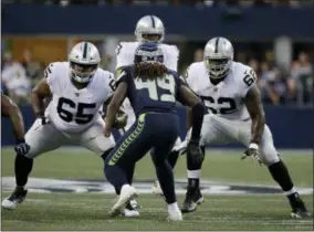  ?? ELAINE THOMPSON — THE ASSOCIATED PRESS FILE ?? In this file photo, Seattle Seahawks linebacker Shaquem Griffin (49) squares off against Oakland Raiders’ Jordan Simmons (65) and James Stone (62) during the first half of an NFL football preseason game in Seattle.