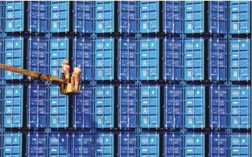  ?? — Reuters ?? Workers fix metal rods to container trunks at a port in Qingdao, Shandong province, China.