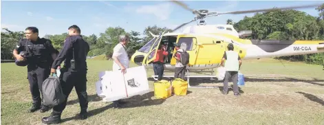  ?? — Bernama photo ?? Election Commission workers using a helicopter to go to Kampung Terian and Kampung Buayan Penampang. Some 400 voters in these two interior villages in Sabah are among 21,173,638 electorate in the country who will cast their votes today.