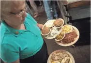  ??  ?? Server Evelyn Ferrell carries meals during lunch.