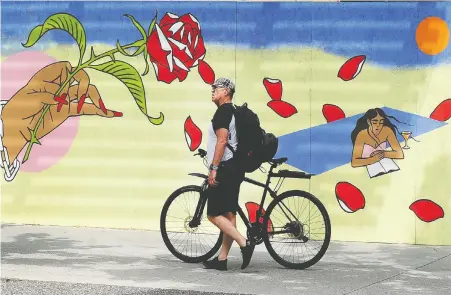  ?? NICK PROCAYLO ?? A cyclist walks past boarded-up stores along Robson Street in early May. Some businesses in the Lower Mainland have had trouble accessing the federal emergency commercial rent assistance program. The B.C. government this week announced a ban on evictions for eligible businesses.